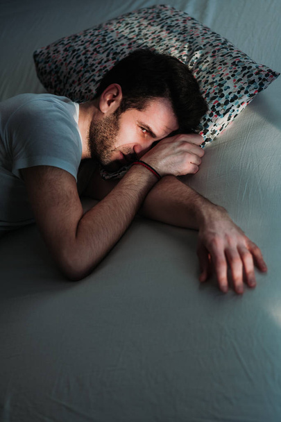 Молодий пригнічений чоловік болить на ліжку
 - Фото, зображення