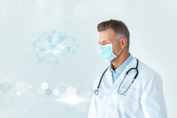 guapo médico en máscara médica mirando la interfaz del cerebro aislado en blanco
 - Foto, Imagen