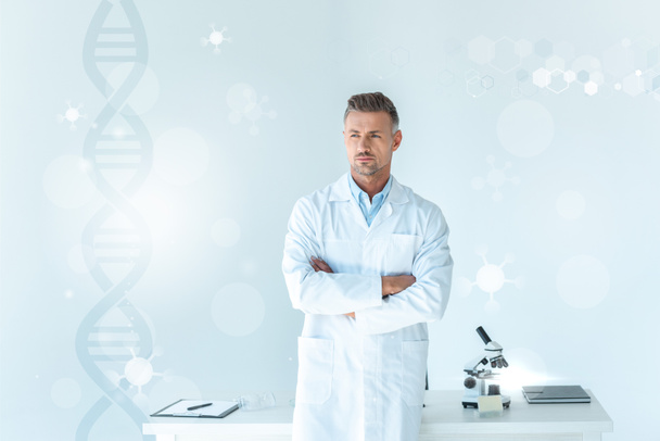 hezký vědec stojící s překřížením rukou u stolu na bílém s dna - Fotografie, Obrázek