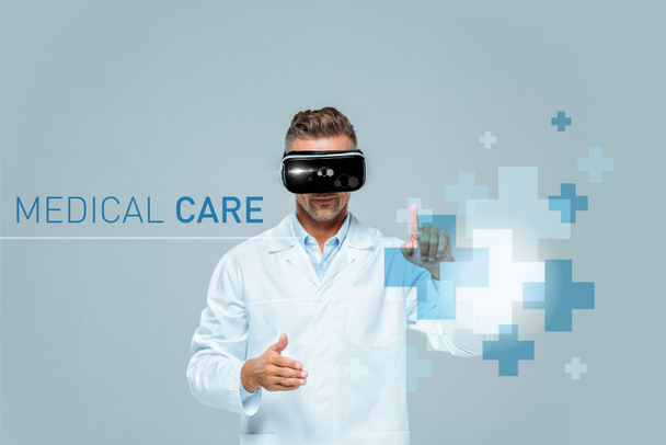 вчений у гарнітурі віртуальної реальності, який торкається медичного інтерфейсу, ізольований на сірій концепції штучного інтелекту
 - Фото, зображення