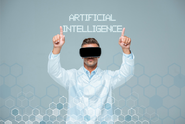 científico en realidad virtual auriculares tocando letras de inteligencia artificial con dos dedos aislados en gris
 - Foto, imagen