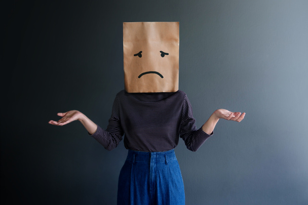 Kundenerlebnis oder menschliches emotionales Konzept. Frau verdeckte ihr Gesicht mit Papiertüte und präsentierte Traurigkeit  - Foto, Bild