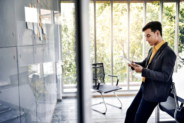 Счастливый молодой бизнесмен работает в зале заседаний офиса с помощью цифрового планшета
 - Фото, изображение