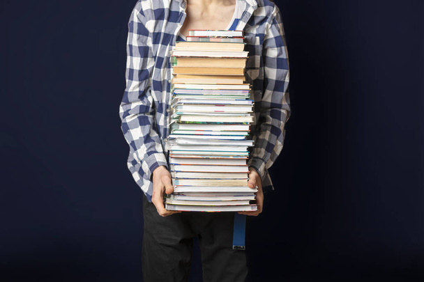 casual student carry huge stack of books on dark background f - Photo, Image
