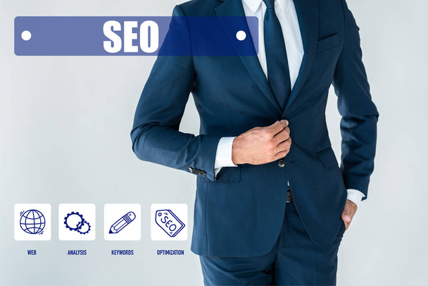 cropped image of businessman buttoning jacket isolated on white with seo icons - Zdjęcie, obraz