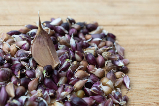 Garlic seeds are on a wooden board against the background of a clove of garlic - Photo, Image