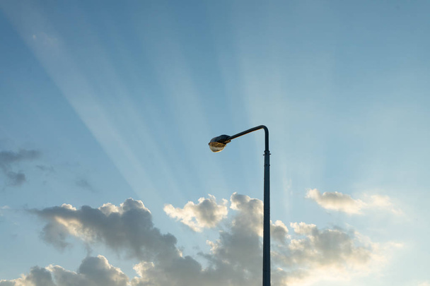 Lamppost on the background of the evening sky with the rays of the setting sun. Copy paste. - 写真・画像