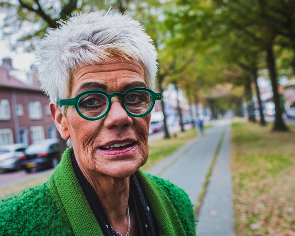 portrait of a senior woman with wrinkles on the skin in the autumn street, outdoor shot - Photo, Image