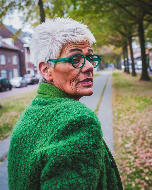 Portrait of a senior woman in the autumn alley of the city, outdoor shot, - Photo, Image