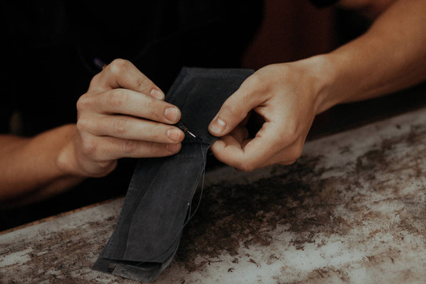 Working process of the leather wallet in the workshop. Man holding leather craft and working. Close up of leather craftsman working with natural leather. Handmade concept. - Foto, afbeelding