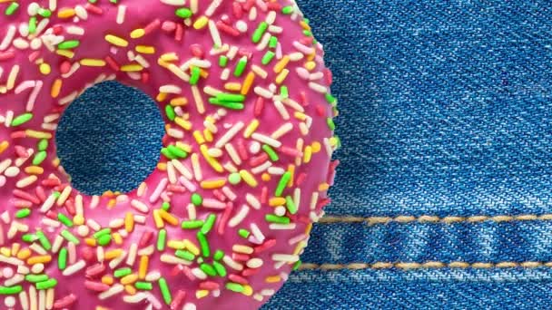 Pink Donut rotating on blue jeans background - Footage, Video