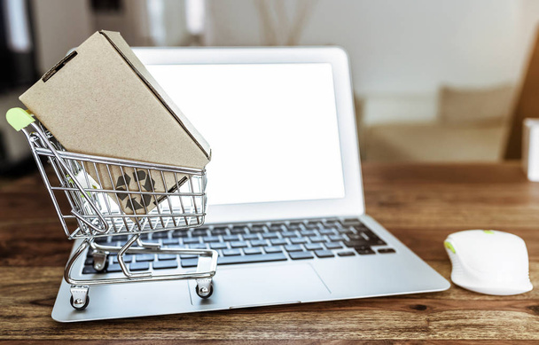 online vásárlás koncepció a miniatűr bevásárló kosár és a laptop számítógép asztal - Fotó, kép