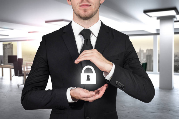 businessman in large modern office protecting lock symbol with his hands - Photo, Image