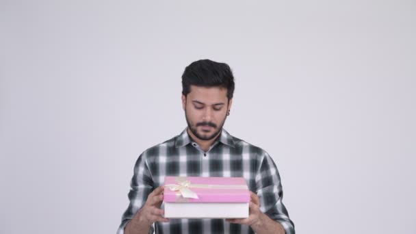 Face of young happy bearded Indian man opening gift box - Video