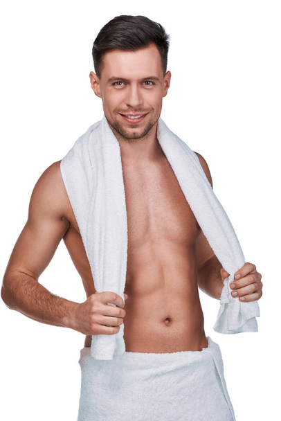 Men's beauty. Portrait of handsome man wrapped in towel and with a towel on his neck looking at camera, isolated on white - Foto, immagini