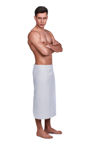 Männerschönheit. Ganzkörperporträt eines gutaussehenden Mannes in Handtuch gehüllt, isoliert auf weiß - Foto, Bild