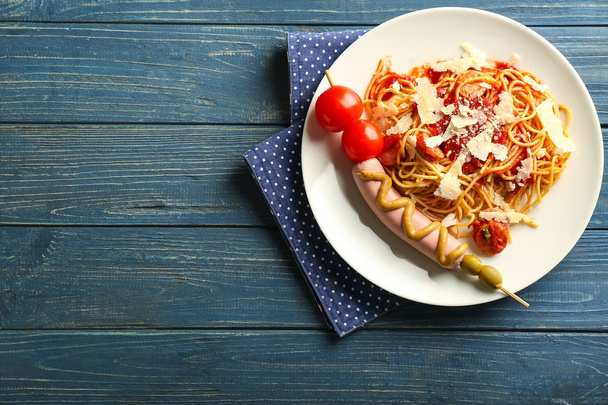 Assiette avec de délicieuses pâtes et saucisses sur table en bois de couleur
 - Photo, image