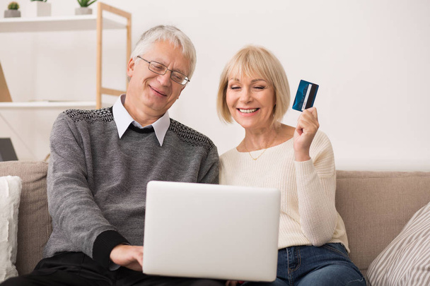 Gelukkig ouder echtpaar online winkelen, met behulp van laptopcomputer - Foto, afbeelding