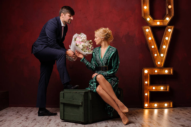 Girl in the green dress sitting on the box gets a bouquet her man - Foto, imagen