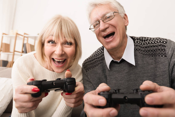 Senior couple playing video games together at home - Photo, Image