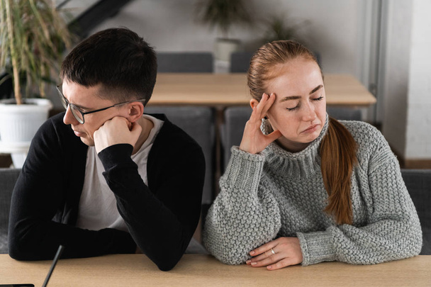 Angry unhappy young couple ignoring not looking at each other after family fight or quarrel, upset thoughtful spouses avoiding talk, sitting silently on couch, having relationship troubles - Foto, Imagen