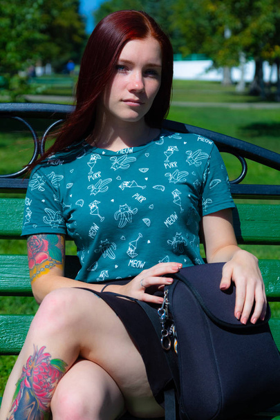 Girl are sitting on the green grass on the background of trees - Foto, imagen