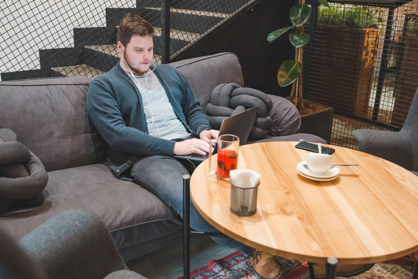 człowiek siedzi w kawiarni z zestawu słuchawkowego i laptopa. Praca w kawiarni. koncepcja freelance. styl życia - Zdjęcie, obraz