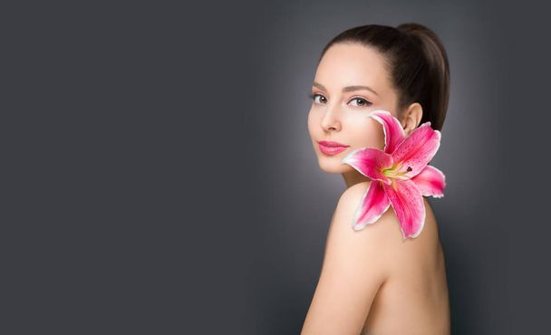 Brunette beauty in light makeup holding colorful lily flower. - Zdjęcie, obraz