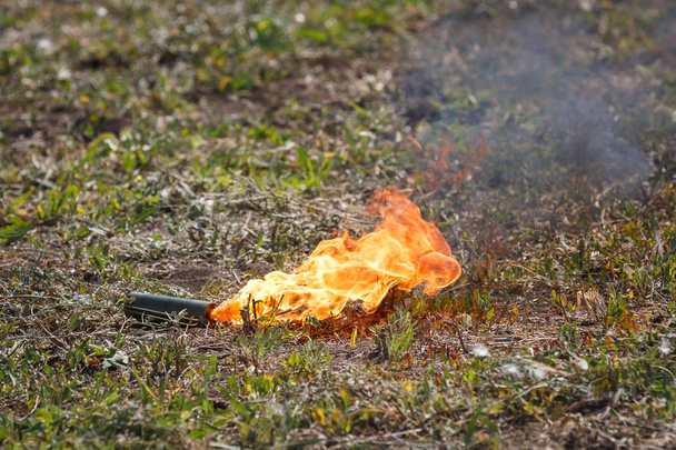 Una granada de humo ardiendo yace en el campo de batalla
 - Foto, imagen