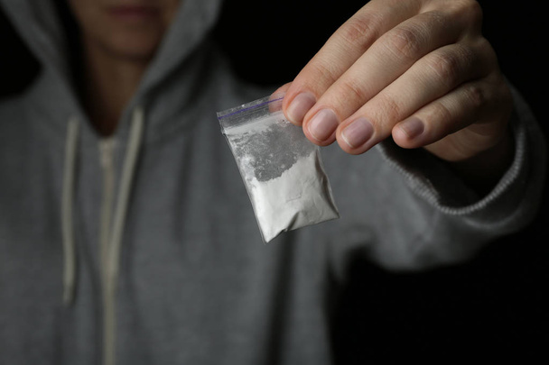 Drug dealer holding bag with cocaine on black background, closeup - Photo, Image