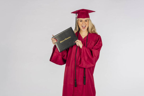 Uma linda modelo loira posando com um diploma após a formatura
 - Foto, Imagem