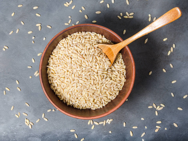 pearl barley in ceramic bowl with wooden spoon on dark background - Foto, Imagem