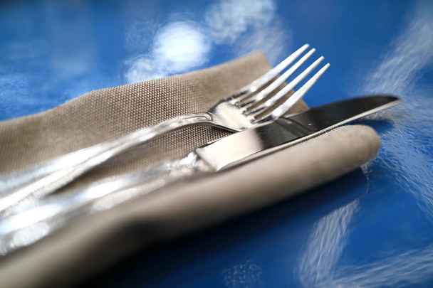 Fork with knife on napkin on blue table - Foto, afbeelding