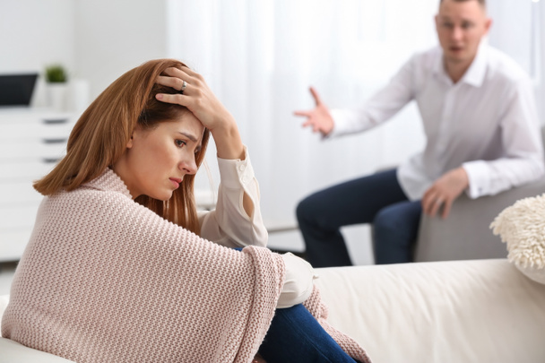 Unhappy woman sitting on sofa while husband shouting at hers. Concept of divorce - Photo, Image