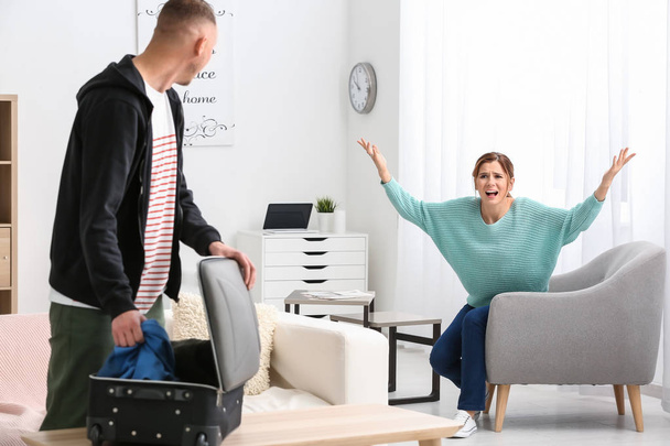 Unhappy man packing belongings while wife shouting at him. Concept of divorce - Photo, Image