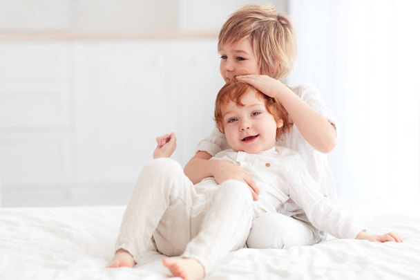 two beautiful kids, brothers cuddling, playing together at home - Foto, imagen