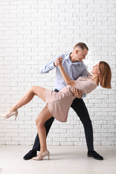 Beautiful couple dancing near white brick wall - Photo, Image
