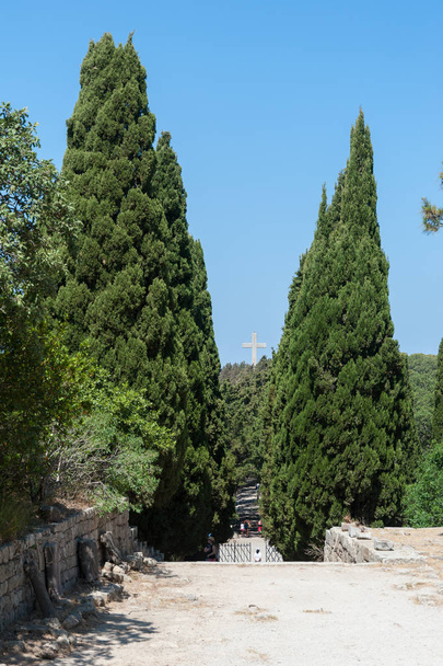 Klasztor Filerimosów, wyspa Rodos, Grecja. W Europie. Grubo zaplanowane drzewa cyprysowe prowadzą z klasztoru na Via Crucis (Kalwaria) w kierunku imponującego krzyża. - Zdjęcie, obraz