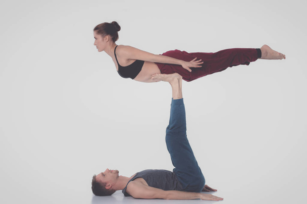 Young athletic couple practicing acroyoga. Balancing in pair. - Foto, afbeelding