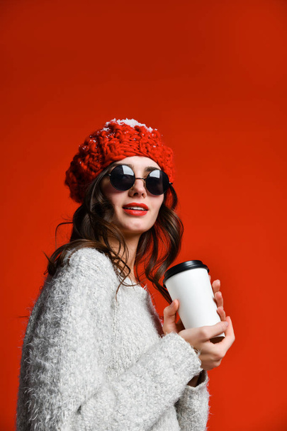 Close up portrait of a smiling young girl in hat holding take away coffee cup - Фото, изображение