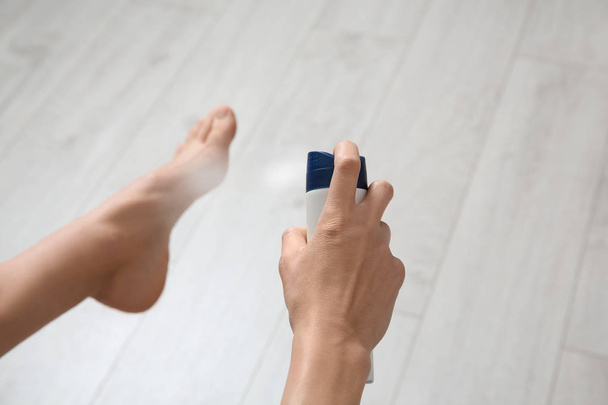 Young woman using deodorant for feet at home, closeup - Fotó, kép