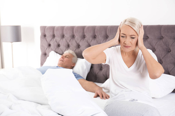 家で眠っている夫の近くにベッドの上に座って動揺の熟女。人間関係の問題 - 写真・画像