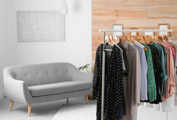 Wardrobe rack with stylish clothes and sofa in dressing room. Space for text - Фото, зображення