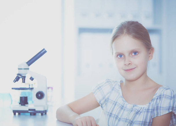Schoolgirl looking through microscope in science class. - Фото, зображення