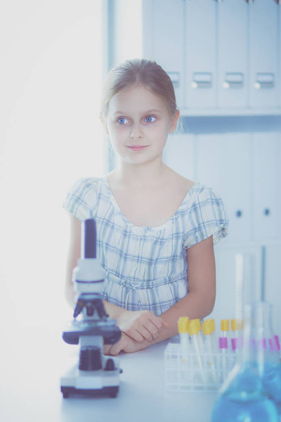 Schoolgirl looking through microscope in science class. - Foto, imagen