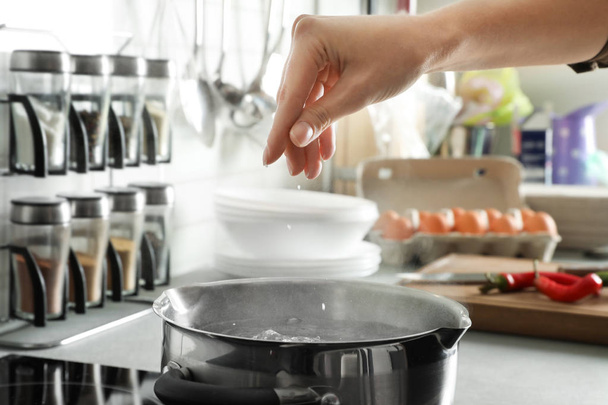 Woman salting boiling water in pot on stove, closeup - Foto, immagini