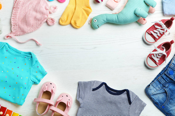 Flat lay composition with cute clothes and space for text on white wooden background. Baby accessories - 写真・画像