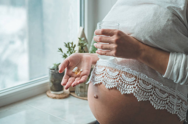 Εννοιολογική φωτογραφία της εγκυμοσύνης υγειονομικής περίθαλψης. Έγκυος γυναίκα παίρνει χάπια κατά τη διάρκεια της εγκυμοσύνης. Τελευταίους μήνες της εγκυμοσύνης.  - Φωτογραφία, εικόνα