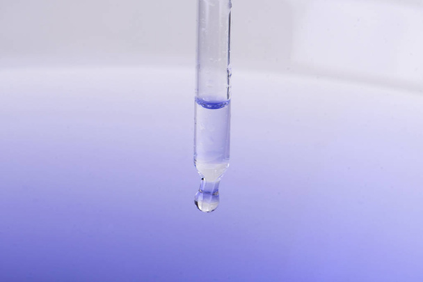 Pipeta sumerge con líquido en agua con reflexión
 - Foto, imagen