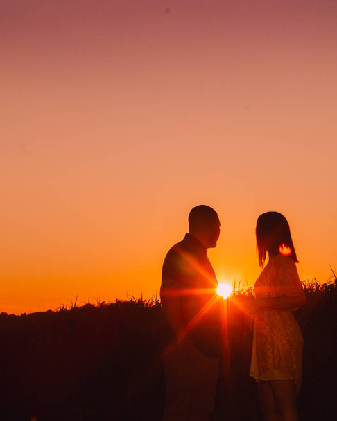 Une jeune silhouette de couple fiancé heureux au coucher du soleil. Deux personnes amoureuses, s'embrassant et se tenant l'une l'autre
. - Photo, image